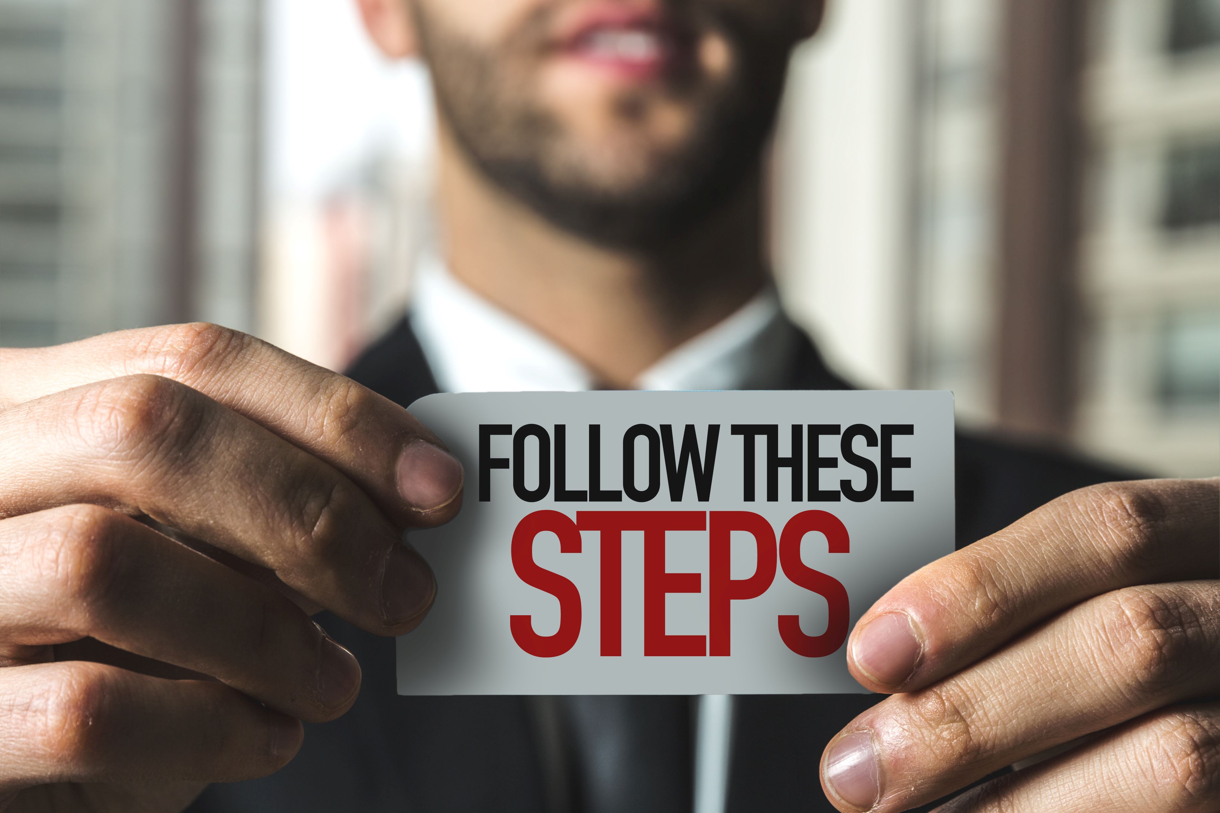 man holding a follow these steps sign